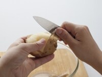 ゆであがったじゃがいもは湯を切り、手で持てるくらいまで冷めたら、皮が裂けているところから皮をひっぱるようにしてむく。芽の部分も丁寧にナイフの根もとの部分をつかって取り除く。