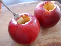 りんごをよく洗ったら、ヘタ周辺にナイフをぐるりと入れ、スプーンでヘタと種を掘り出します。<br />