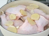 鍋に2・鶏骨付き肉を入れて水900ｍｌ・酒を入れ生姜とにんにく・塩を加えて火にかける。