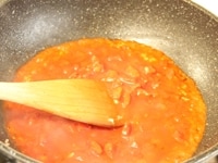みじん切りにしたニンニクとカットトマト缶をフライパンに入れ、汁気がなくなるまで煮ます。