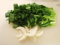 小松菜は軸を取り除いて水洗いし、2～3cmの長さに切ります。たまねぎは皮をむきくし形に切ります。