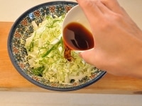 白菜と大葉の千切りを器で混ぜ合わせ、まずポン酢とオリーブオイルを回しかけます。