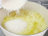 鍋にオリーブ油・にんにくを熱し、香りが出たら玉ねぎを加え炒める。玉ねぎがしんなりしたら2を加え、沸騰したら洗っていない米を加える。<br />