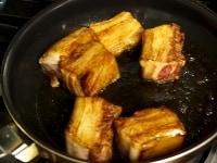 豚ばら肉は5～6cm角に切ってボールに入れ、醤油をかけてよく揉み、フライパンで各面を2分ずつ弱火で焼く。