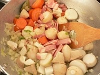 里芋、にんじん、エリンギ、ベーコンを加えて軽く炒める。<br />