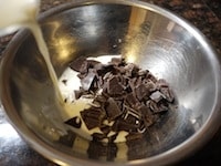 生クリームを600wの電子レンジに1分かけて、沸騰させます。&nbsp;細かく砕いたチョコレートをボウルに入れ、生クリームを加えます。