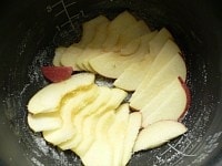 内釜の下半分ほどにバターを薄く塗り、グラニュー糖小さじ1をふりかけて釜を回して広げ、薄く切ったリンゴを敷き詰め、グラニュー糖小さじ1をふりかける。<br />