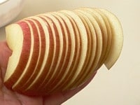 リンゴは芯をくり抜き、薄く切る。手の平で斜めに倒して見て、裏表の、どちらが綺麗か見定める。<br />