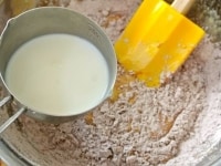 粉類の半量を3に加え、ゴムベラなどでざっと混ぜたら牛乳の半量を加えて、底から返すように大きく混ぜます。同じ作業を繰り返して粉類と牛乳を全て加え、粉っぽさがなくなるまでさっくり混ぜ合わせます。