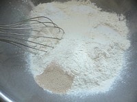 強力粉、ドライイースト、ミルク、砂糖、塩をボウルに入れて泡だて器でグルグル混ぜる。<br />