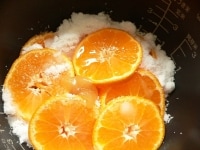みかんを半分入れ、砂糖を入れ、残りのみかんを入れ、レモン汁とハチミツを入れて普通に炊く。<br />