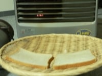 パンを盆ザルに並べ、金属製のボウルの上にのせ、ファンヒーターの前で1時間ほど乾燥させる。<br />