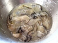 牡蠣の下処理をします。<br />
牡蠣に塩、片栗粉、水を加え、手で揉んだら、洗い流します。<br />
キッチンペーパーで水気をおさえます。