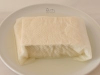 豆腐はキッチンペーパーに包んで軽く重しをし、20分ほどおいて水気をきる。<br />
