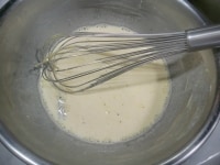 5に6を少しずつ加え、ホイッパーで混ぜる。6の入っていた手鍋にザルで漉しながら戻していく。ここで、バニラのさやは取り除く。<br />