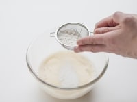 牛乳とバターを小鍋に入れ沸騰直前まであたためたら卵液にすこしずつ加え混ぜる。小麦粉も茶こしなどでふるい入れ手早く混ぜる。