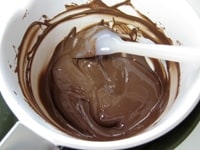 板チョコレートはラインに沿って割り、小鍋かボウルに入れ、湯をはったボウルにつけ、スパチュラで混ぜながら溶かします。