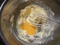 解きほぐした卵を2～3回に分けて加え、そのつど、泡立て器でよく混ぜます。