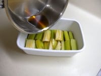 容器（ビンなど）にセロリを並べ、上から冷めた漬け汁をまわしかけます。種を取り除き、輪切りした赤唐辛子を加えます。
