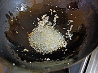 ゴーヤーは縦半分に切り、スプーンで種とワタをしっかりとる。3mm幅に切り、塩(分量外)を加えた熱湯で軽く茹でる。卵は空気をふくませるようにかき混ぜておく。<br />
フライパンにグレープシードオイル、ニンニクを入れて弱火にかける。