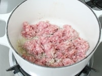 鍋ににんにく・オリーブ油を熱し、香りが出たら挽き肉を加えて炒める。肉を入れたらあまりかき混ぜずに焼くようにして火を通す。