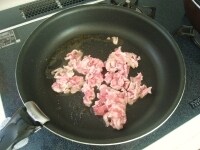 フライパンにごま油を入れて熱し、豚小間肉を加えて色が変わるまで炒めます。