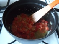 香りが出たら、玉葱を加えてしんなりするまで炒め、トマトを加えて混ぜ合わせます。<br />