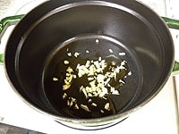 鍋に、みじん切りのニンニクとサラダ油を入れ、中火にかけます。<br />