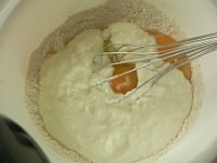 粉の中ほどにヨーグルトと卵を入れ、初めに液体部分をグルグル混ぜる。<br />