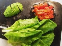 トマトは1cm角に、アボカドは縦二等分にし、種を取って皮をむき半月型に切ります。サラダ菜は根元から取っておきます。<br />