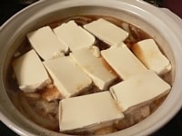 玉ねぎがしんなりと煮えたら、豆腐を敷き詰めるように並べて煮る。<br />