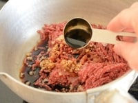牛ひき肉、調味料、生姜のみじん切りをすべて鍋に合わせ、調味料を溶かし混ぜます。<br />