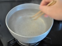 塩と酢を加えたら、箸をぐるぐると回して調味料を溶かし、渦を作ります。火加減は弱火にしておきます。