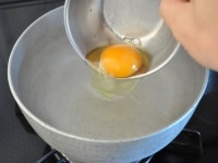 別容器に割り入れておいた卵をそっと渦の中心に落とします。
