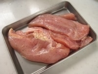 バットに鶏胸肉を並べ、塩とブラックペッパーを全体にふり下味をつけます。そのまま5分ほどおきます。<br />