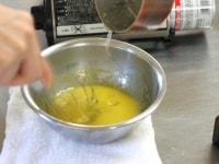 １の卵黄に、シロップをひものように垂らしながら加え、泡立て器で手早く混ぜます。