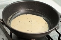 （4）のフライパンにアンチョビ、牛乳、おろしにんにくを入れて中火で温め、塩こしょうで味を調えます。