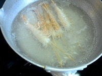 鍋に湯を沸かして塩ひとつまみ（分量外）を加え、まず三つ葉をさっとゆでて取り出し、冷水に取って色止めをします。<br />
<br />
続いて、串を刺した状態のえびを2分ほどゆでます。ゆでたら冷水に取り、熱が取れてから竹串と殻を取り除きます。殻をむいたえびは見栄えをよくするために両端を切り落としておきます。<br />
