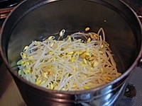 大豆もやしはひげ根をとる。<br />
鍋に大豆もやし、大豆もやしの半量の水、塩少々(分量外)を入れてふたをし、6～7分間茹でる。水気を切る。