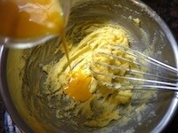 解きほぐした卵を2～3回に分けて加え、そのつど、泡立て器で分離しないように気をつけながら、よく混ぜます。分離しそうになったら、ホットケーキミックスを大さじ1加え、混ぜるようにします。