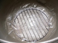 発酵途中でニンニクから出る水分でニンニクがふやけてしまわぬよう、保温ジャーの底にケーキクーラーを敷く。<br />