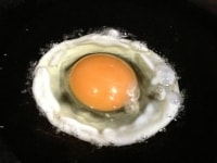 卵を割り入れます。焼くというよりも揚げる感じで、周りの油をお玉やスプーンですくって、黄身の上からかけて、好みの固さに仕上げます。<br />