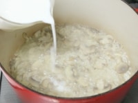 6のスープが少なくなってきたら牛乳を少し加える。焦げ付かないように時々混ぜながら米が水分を吸ったらまた牛乳を加える。これを繰り返し、16～18分加熱する。