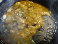 ヘラで卵をくずしながら、牡蠣をとじて完成。もやしの上に盛り付け、香菜とニンニクチップをのせる。<br />