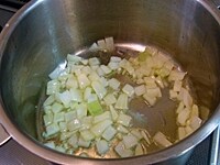 鍋にニンニクとオリーブオイルを入れて弱火にかけ、香りが出たら玉ねぎを入れて炒める。<br />