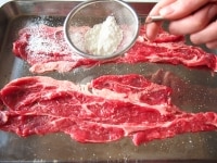 牛肉は両面に塩、胡椒をし、茶漉しで小麦粉をまぶし、余分な粉ははたきます。<br />
（肉に厚みがあれば、１枚を半分に切って１枚ずつラップに挟み、更に薄くなるまで肉たたきでのばします）<br />