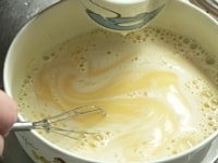 温めた牛乳を少しずつ加えながら混ぜ、ラップなしで600Wのレンジで4分ほど加熱する。加熱途中で3～4回混ぜて、とろりと仕上げる。<br />