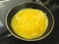 卵を割りほぐし、テフロン加工のフライパンに流して薄焼き卵を作ります。弱火でじっくり焼き、卵のまわりが浮いてきて表面が全体的に乾いてきたら、菜箸に半円状にひっかけてひっくり返します。