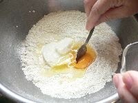粉の真ん中に豆腐、サラダ油、卵を入れる。卵黄を少し（1/4程度）スプーンですくって取り置く。