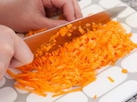 にんじんをみじん切りにしてボウルに入れ、ラップをかけてレンジで2分くらい加熱する。<br />